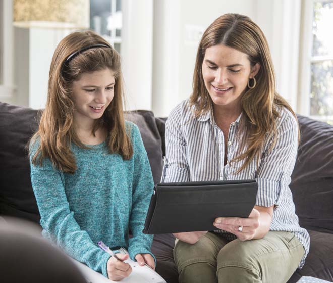 Mother and Daughter sitting on the couch, looking at the tablet