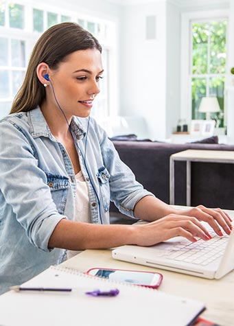 Photo of a female college student listening to Learning Ally audiobooks on a laptop